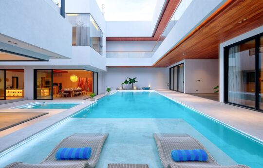 Swimming pool of villa with 2 day beds and villa exteriors