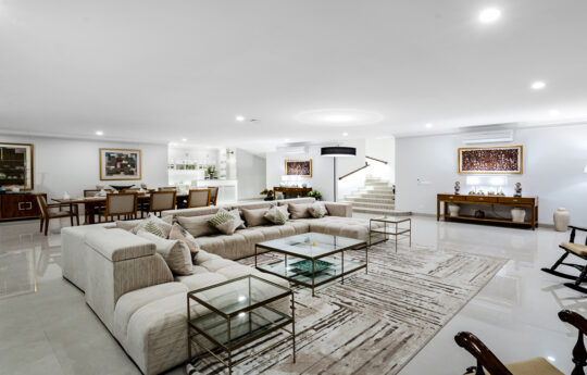 Spacious living area of villa with massive sofa and coffee tables