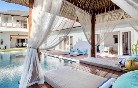 View of swimming pool from pool side gazebo with two mats and coconut