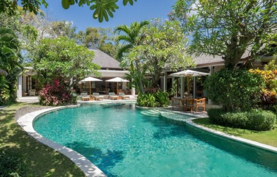 Swimming pool view with villa exterior on sunny day and garden