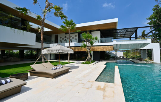 Swimming pool, day beds and pool side area with 2 level villa in background