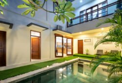 Swimming pool at night with villa exterior glimpses