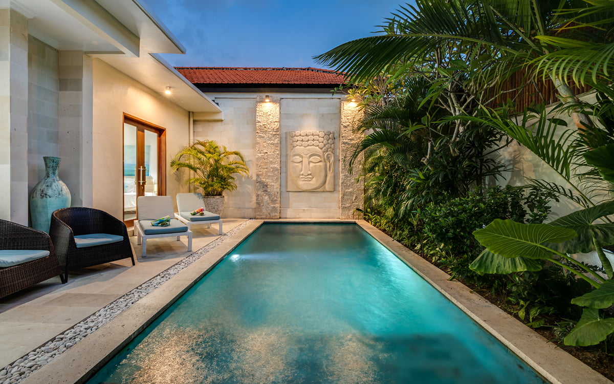Swimming pool at night with balinese statue at end of pool