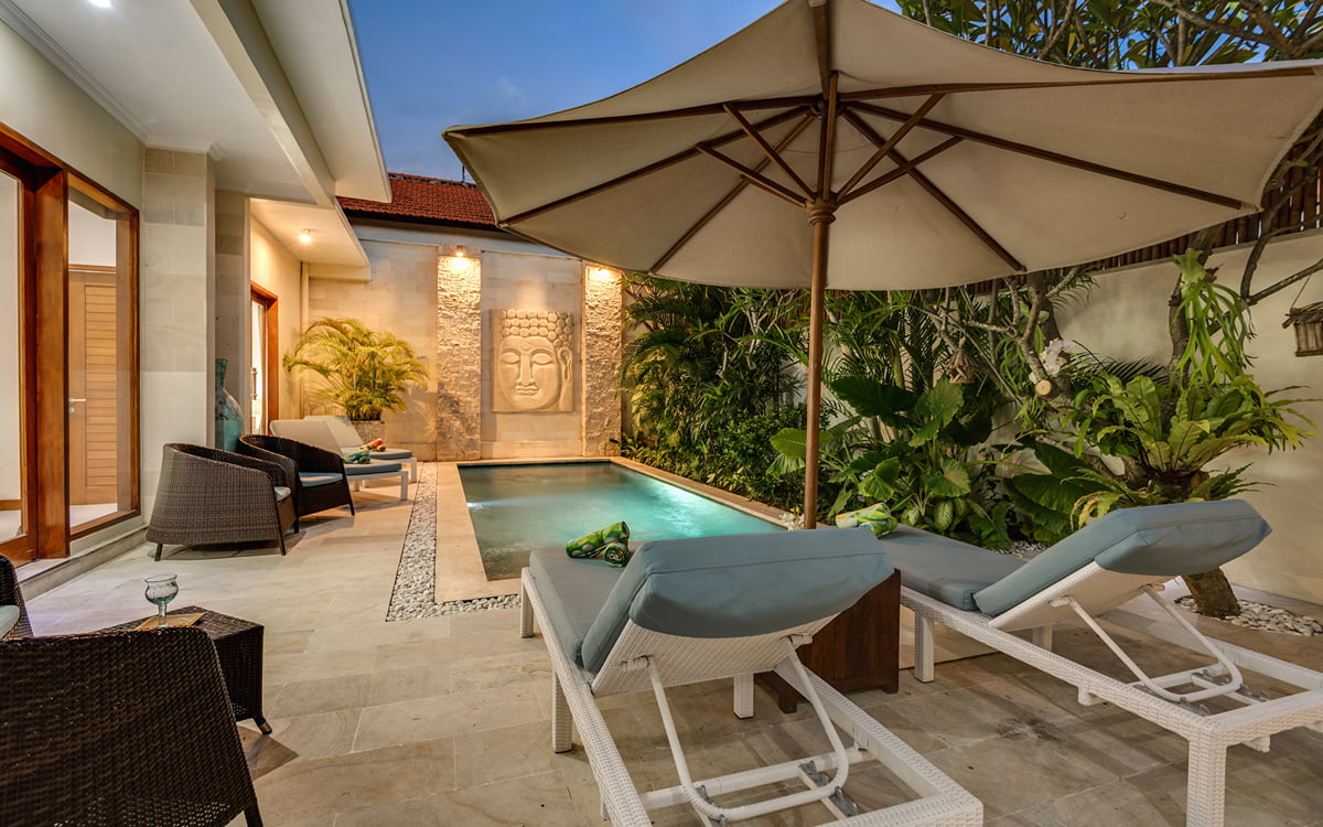 Expansive view of swimming pool and deck area with 2 day beds and villa exterior at night