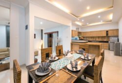 Dining table of villa with seating for six people and view of kitchen