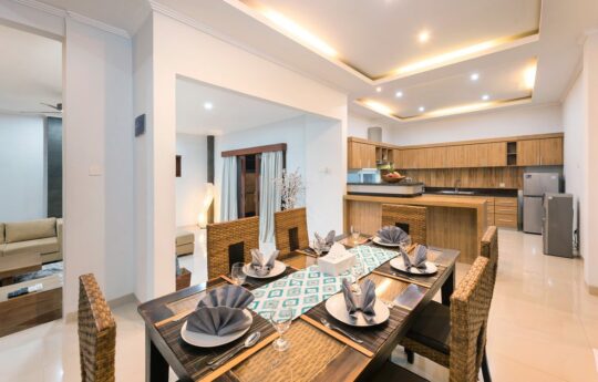 Dining table of villa with seating for six people and view of kitchen