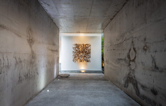 Concrete walkway entrance of villa with statue at end