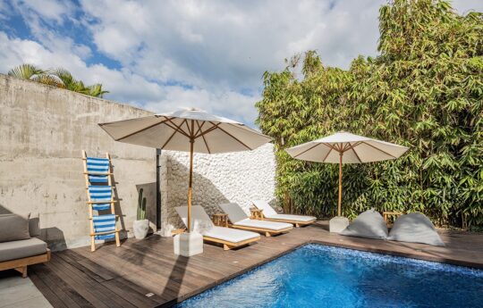Swimming pool with day beds of villa and two large umbrellas