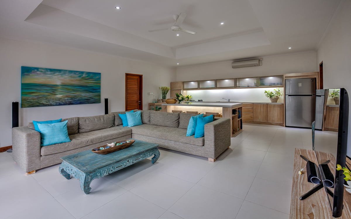 Open plan living space of villa with L shaped sofa and kitchen