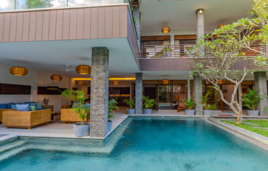 L shaped swimming pool with two level villa in background