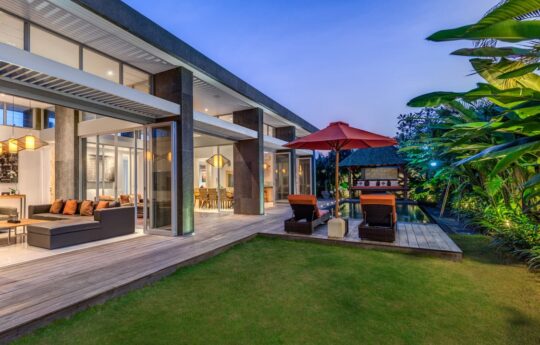 Exterior view of Villa Indah at night with lights on and garden in foreground