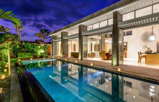 Villa Bamboo Villa Bamboo swimming pool and sunbeds with view of interiors at night with lights on