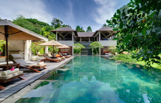 Villa Arsana Estate Large swimming pool with garden and villa exteriors with day beds by the pool on sunny day