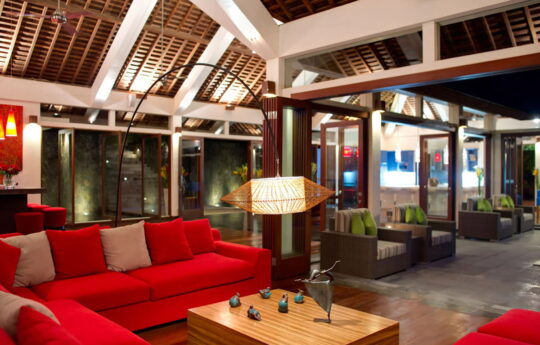 L shaped red sofa and coffee table in lounge area of villa