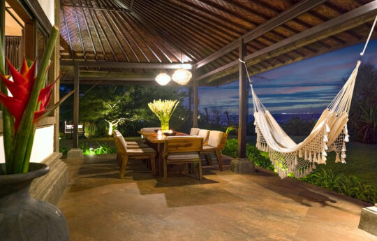 Terrace area with dining table and hammock at dusk