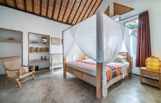 King size bed in bedroom with chair and mosquito net