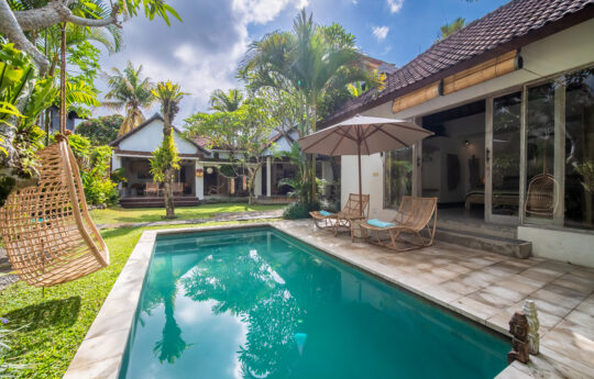 Swimming pool with gargen views and lounge chairs of villa