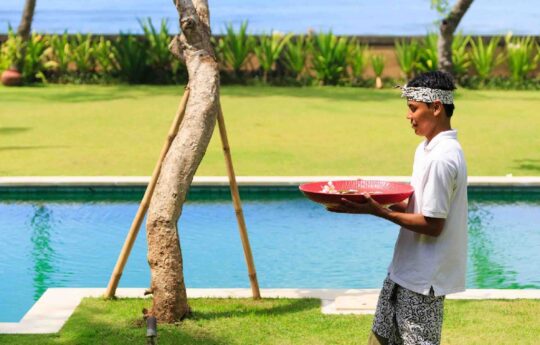 Balinese staff next to swimming pool serving drinks