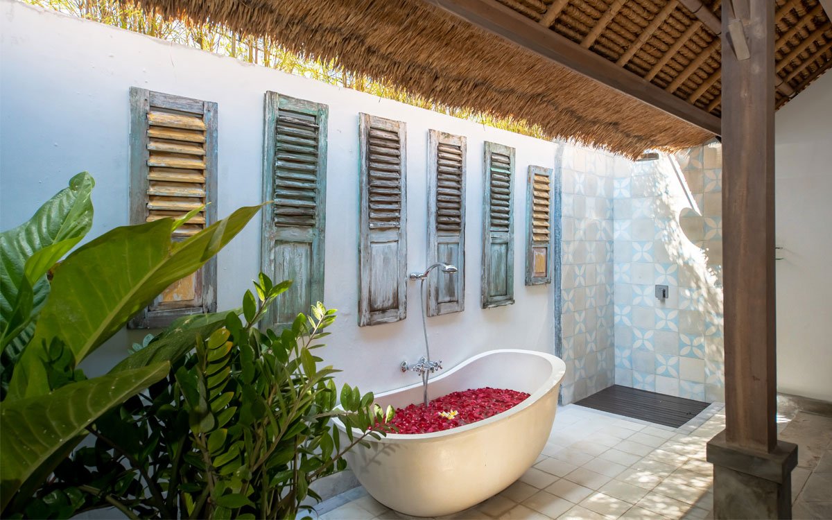 Rustic outdoor bathroom with bathtub full of petals