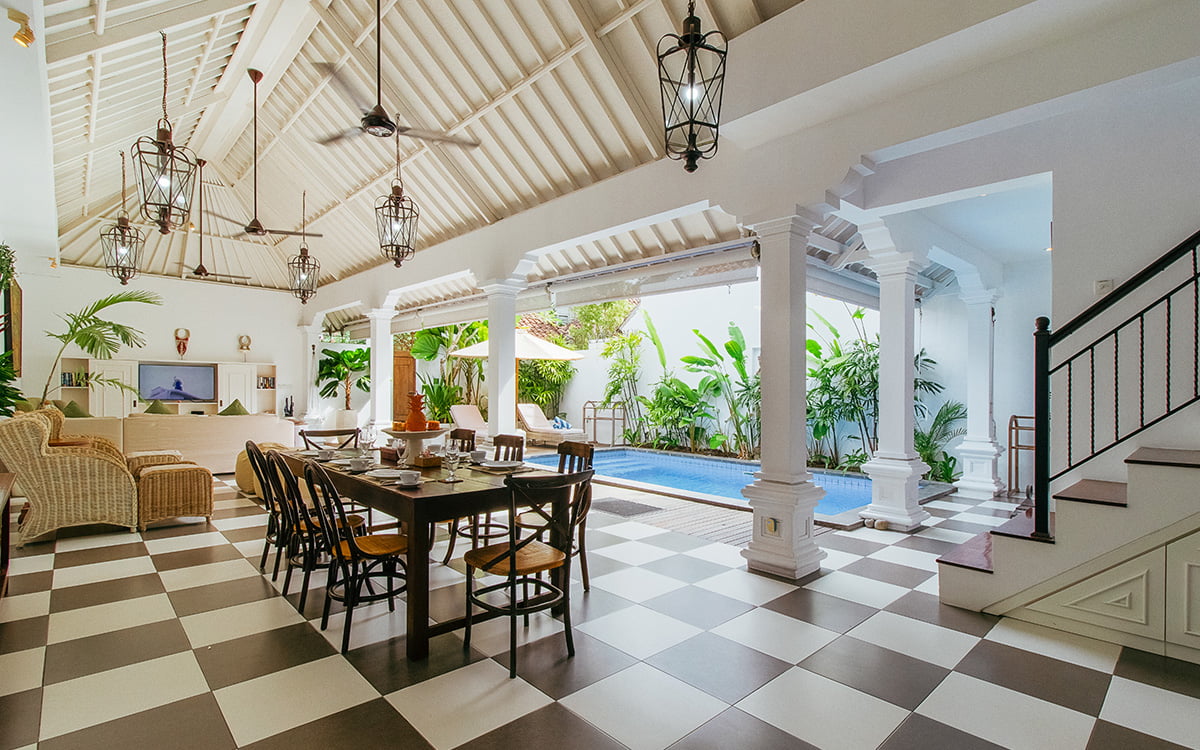 Open plan tropical living areas of villa with swimming pool in background