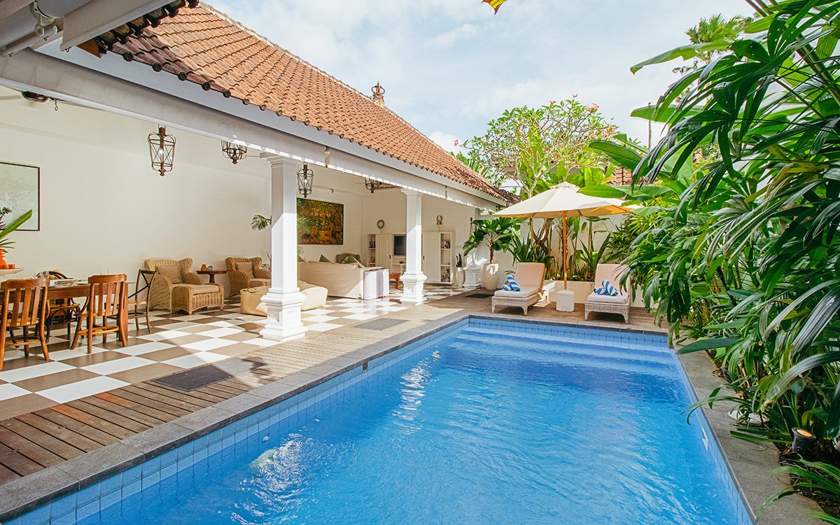 Swimming pool with day beds in background and villa exterior