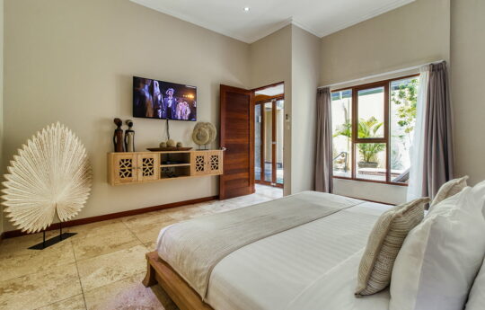 Modern bedroom of villa with flat screen tv mounted on wall with garden views
