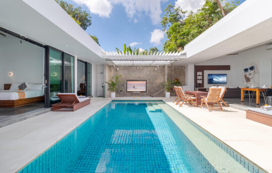 Villa Khalifah Alif Seminyak large sunny swimming pool with modern villa exteriors and day beds