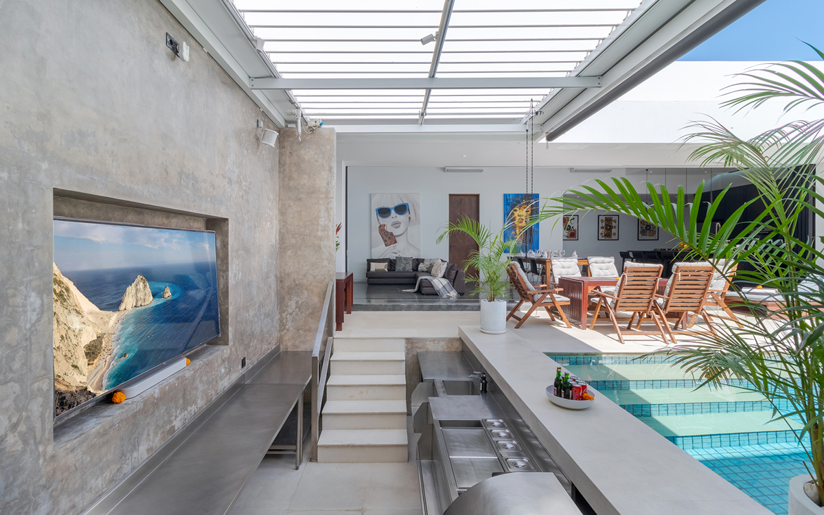 Sunken BBQ area of swimming pool with TV mounted on wall