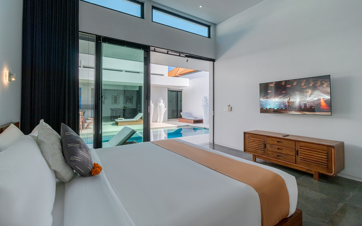 bedroom of villa with flat screen tv and king bed with views to pool