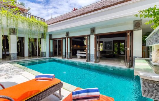 Swimming pool on sunny day with villa exterior