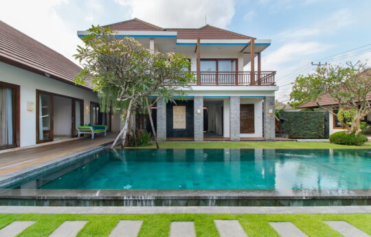 View of villa exterior with pool in foreground and garden area