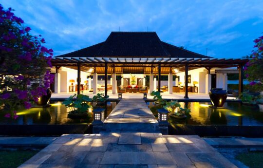 Villa at night with lights on and view of open plan lounge areas