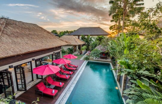 Swimming pool, deck chairs and garden views of Villa Nilaya at dusk