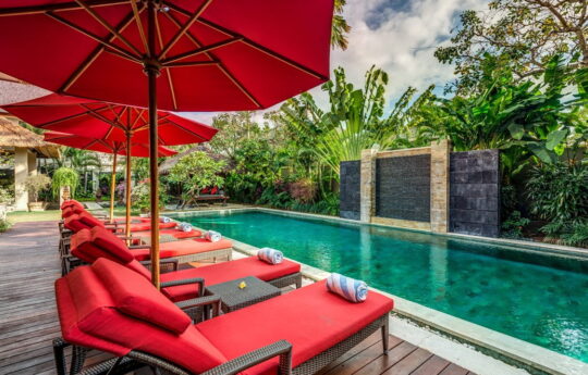 Day beds by tropical swimming pool and lush garden