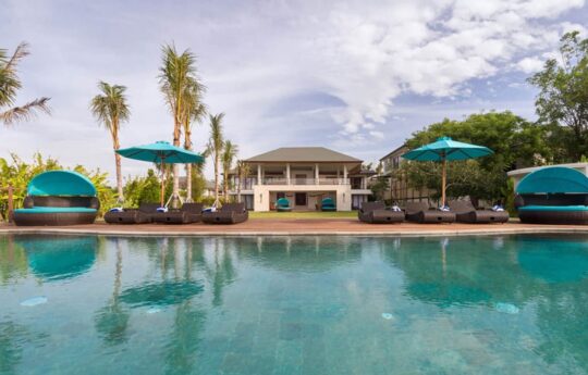 Swimming pool with villa exterior views with day beds
