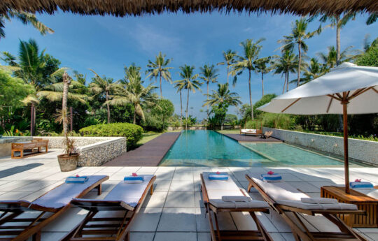 Day beds next to swimming pool under gazebo