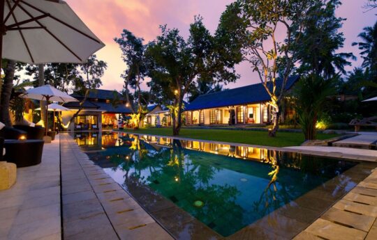 swimming. pool at night with villa exterior with lights on