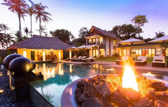 Swimming pool at night with villa in background