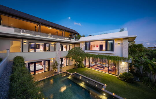 Two level villa at night with views to pool and garden from above
