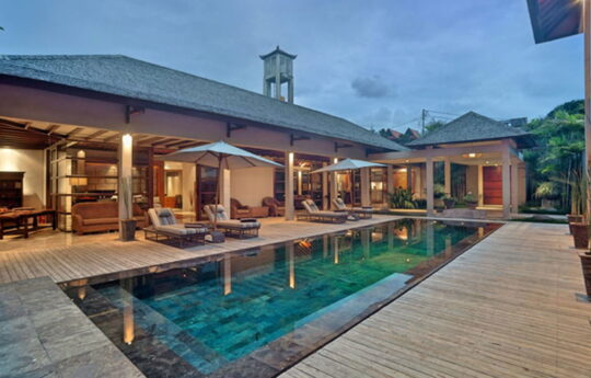 Day beds by a swimming pool with villa exterior living areas