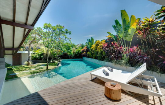 Sunny private swimming pool with deck area and sun loungers of villa