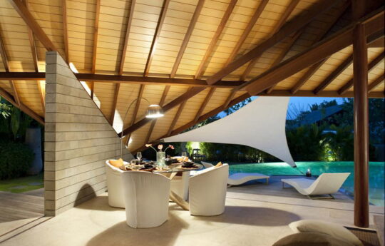 Living area of villa at dusk with pool in background