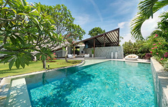 View of sunny swimming pool with architectural designed villa in background