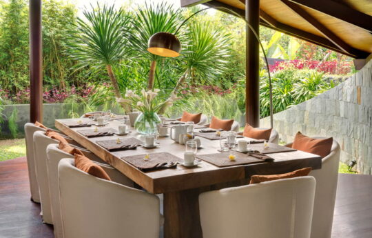 Dining table of villa with lush tropical garden views