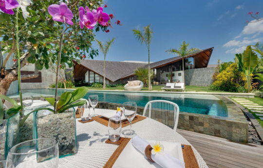 4 bedroom The Layar VIlla in Seminyak, Bali Swimming pool on sunny day with villa in background and breakfast table in foreground