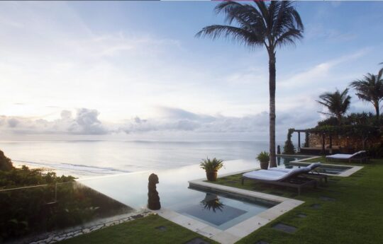 view to calm ocean at sunset with pool in foreground