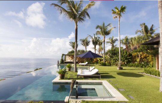 oceanfront villa with pool views and grassy area on sunny day