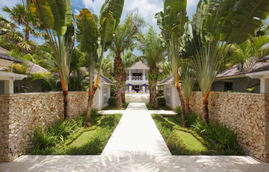 Stone pathway entrance of villa with main villa exterior in background