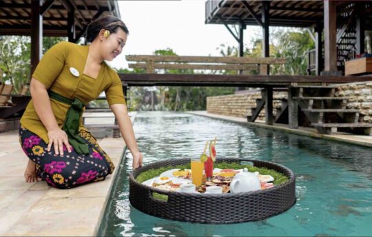 Balinese staff preparing floating breakfast in swimming pool