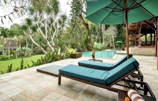 day beds and deck area of villa with swimming pool and garden views